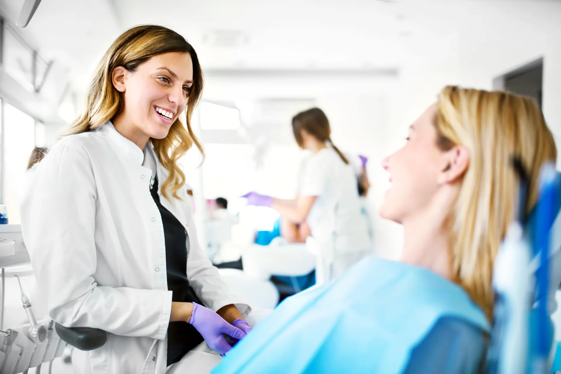 A dentist smiling with her patient in the treatment chair