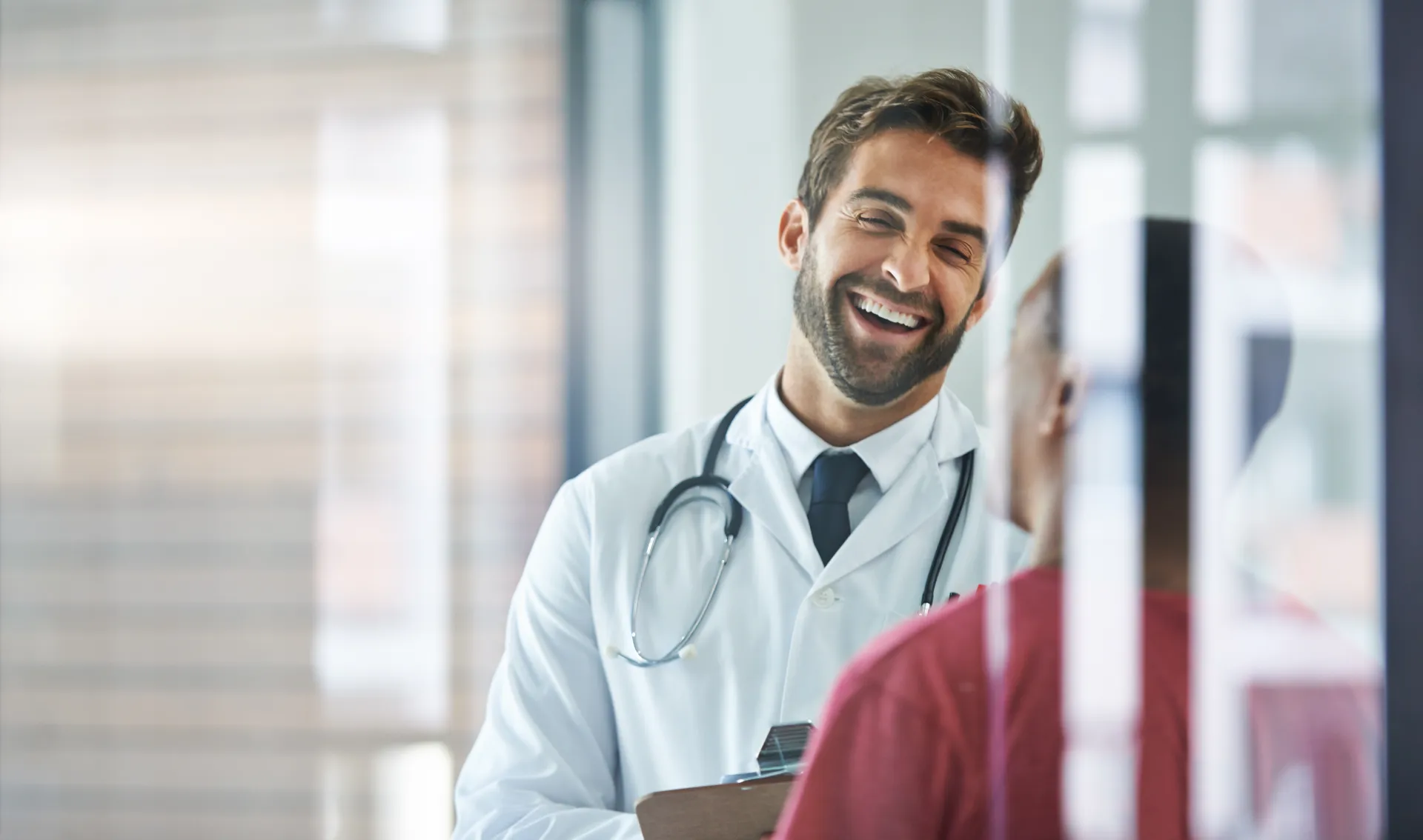 A doctor laughing with a patient in a bright office